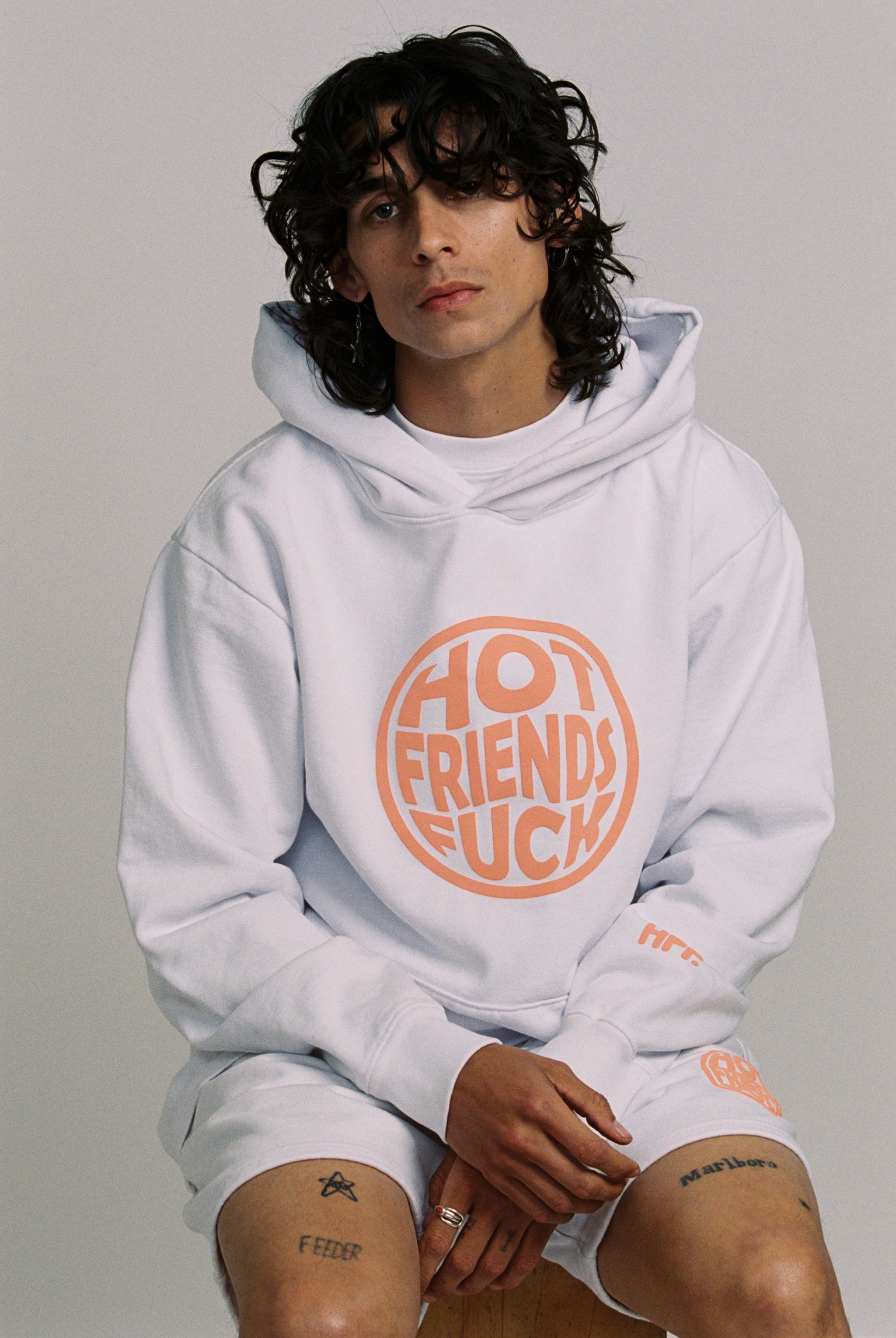 Donovan is wearing the White Hoodie with Salmon Pink Puff Print. 20oz French Terry