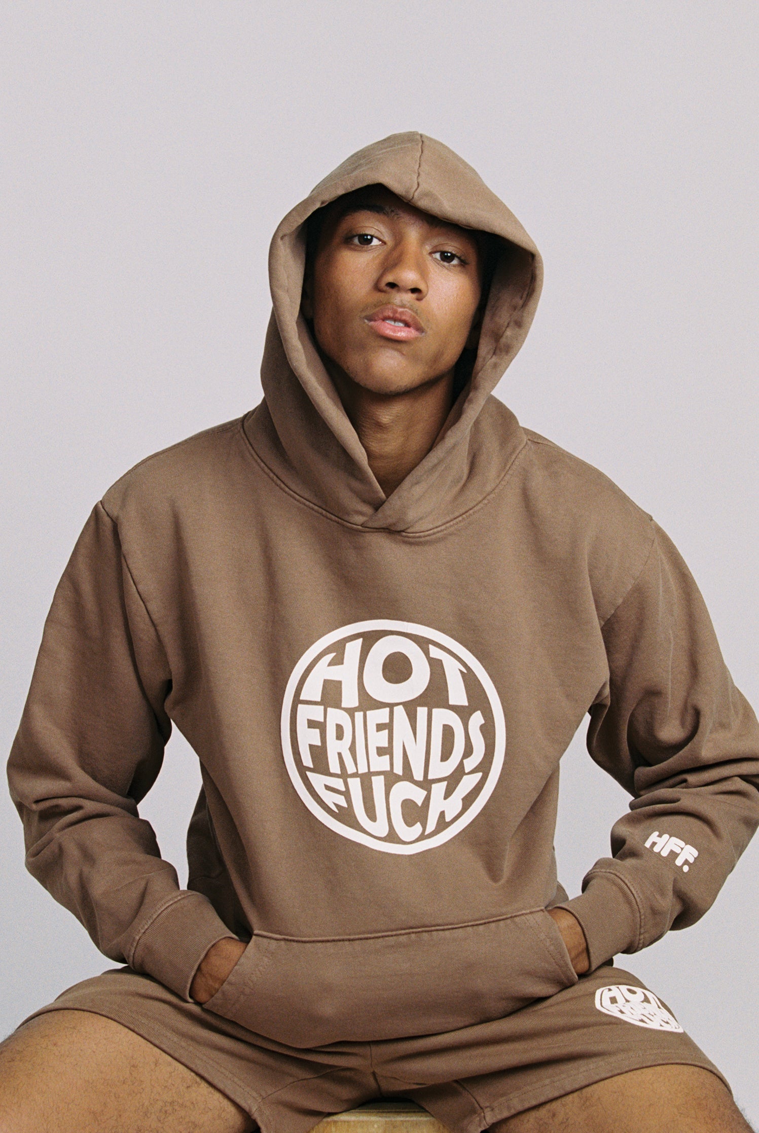 Hechan is wearing the Brown Hoodie with White Puff Print. 20oz French Terry