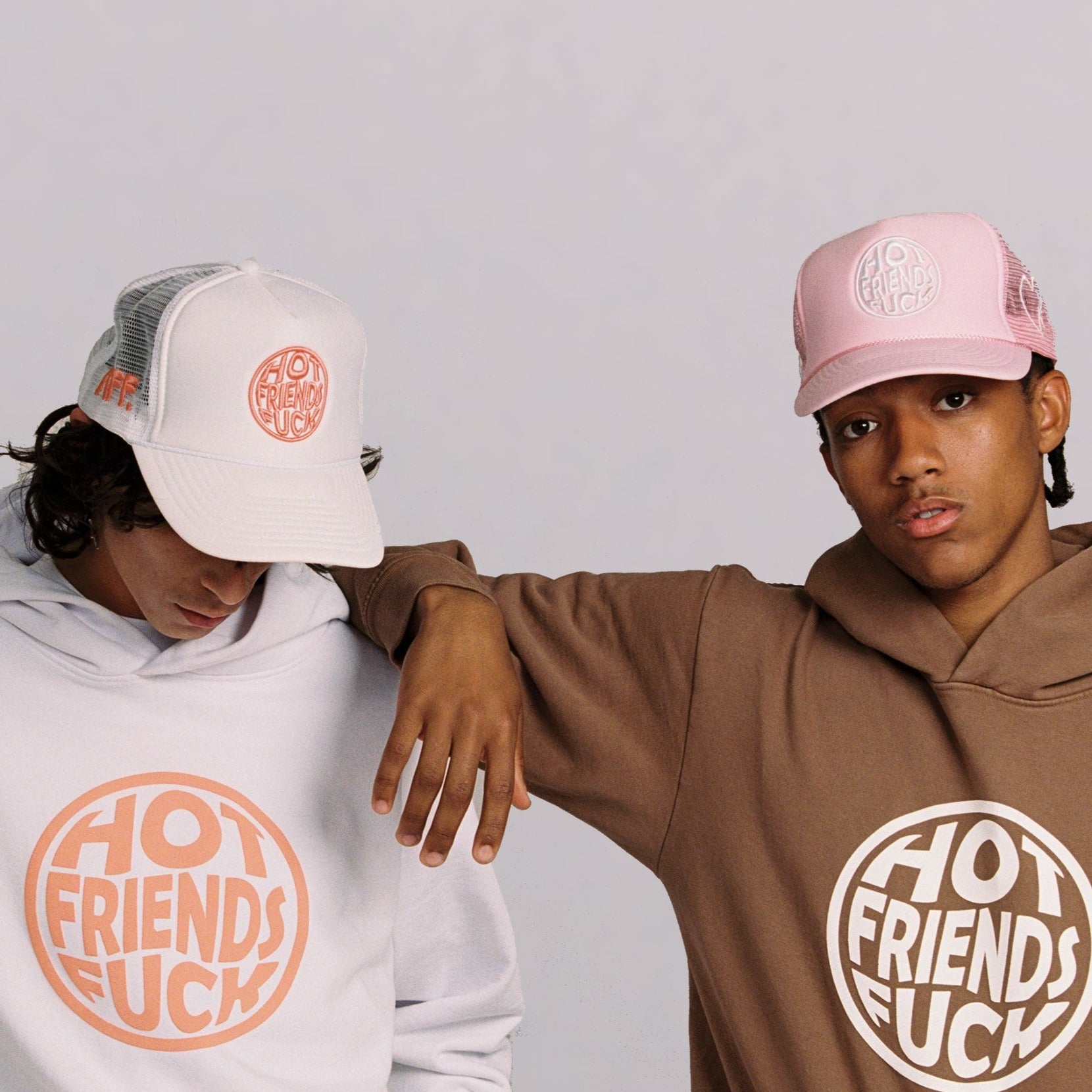 Donovan is wearing the Cream Hat with Salmon Pink Embroidery, and Hechan is wearing the Pink Hat with White Embroidery